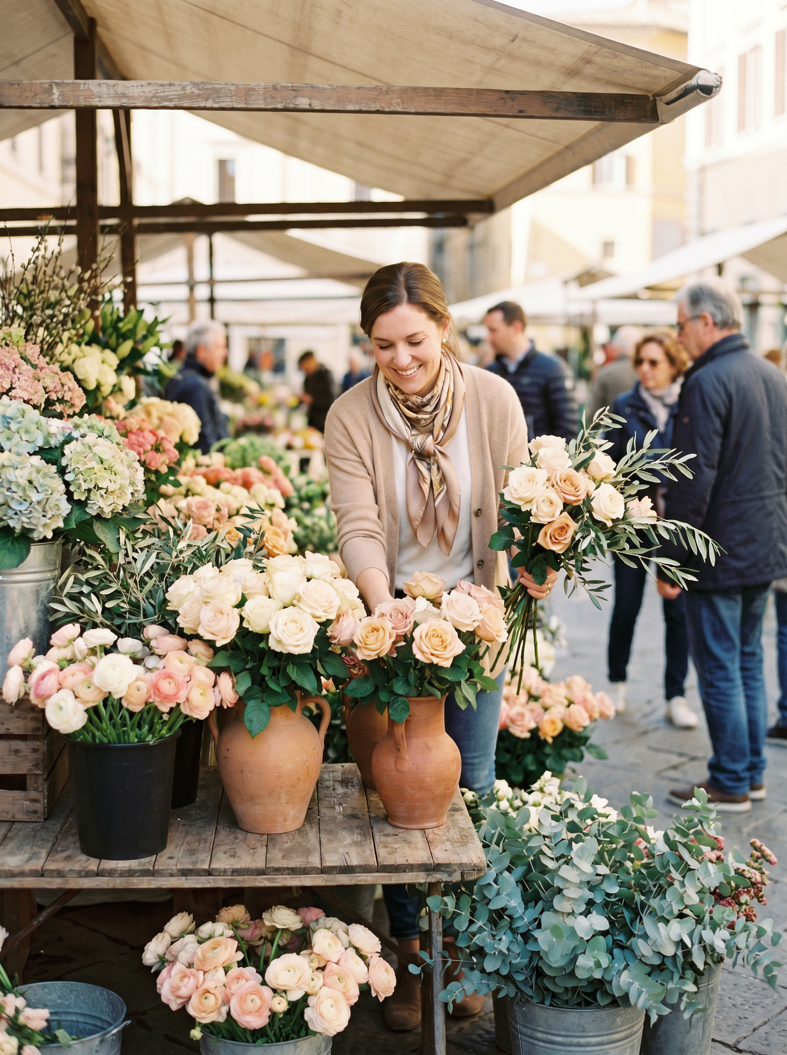 A woman arranging fresh cut flowers at a European flower market stall