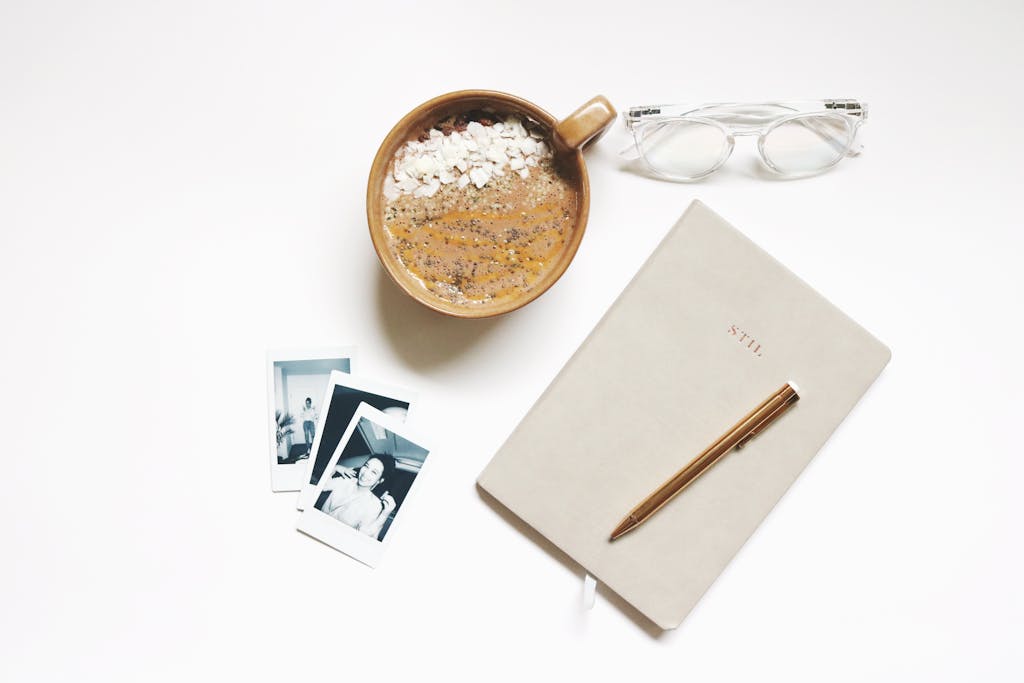 Minimalist flatlay featuring a coffee, notebook, eyeglasses, and photographs.